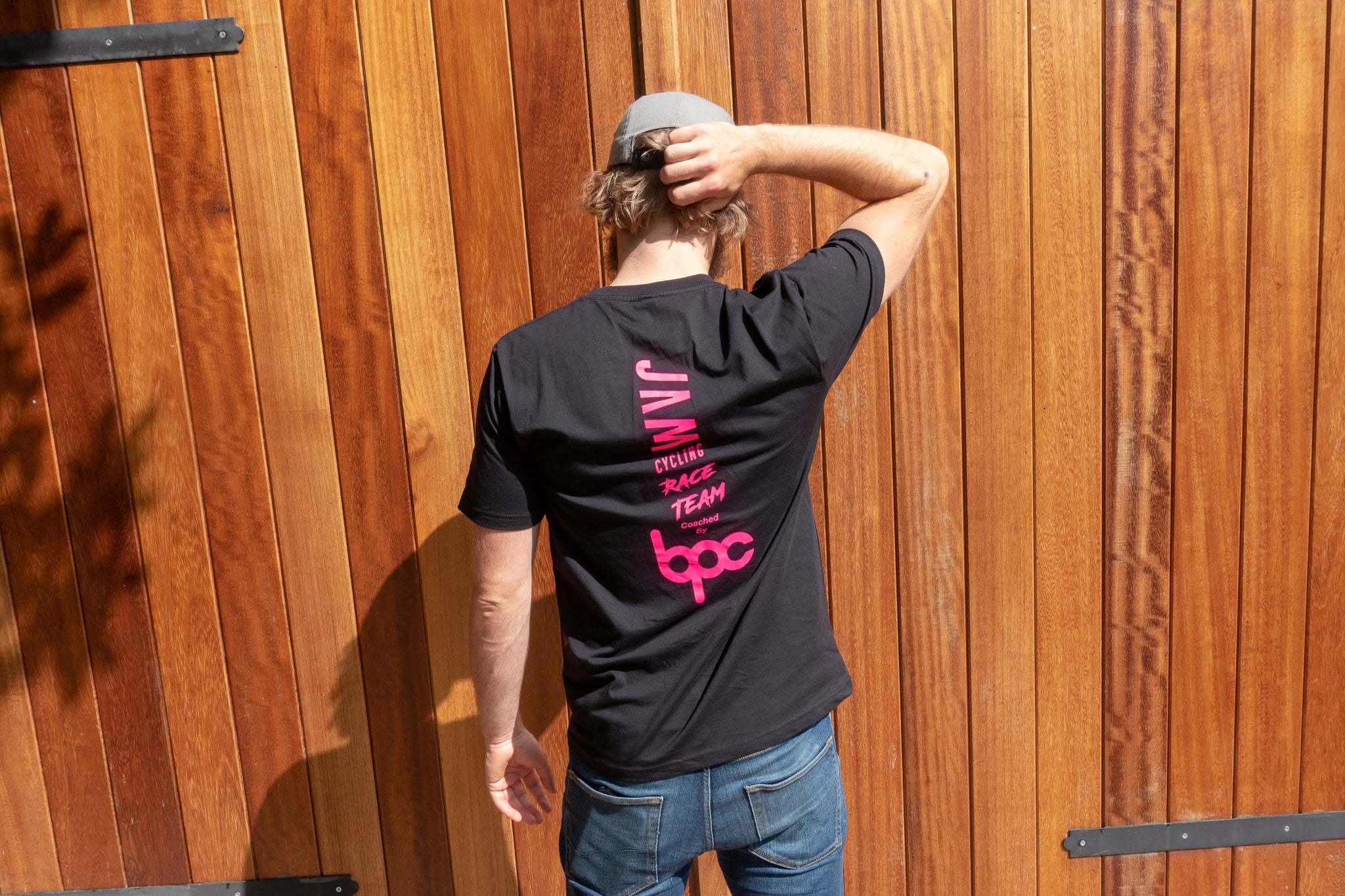Black JAM Race team t-shirt featuring HOT logos worn by Jam CEO with blue jeans and brown beltagainst barn door