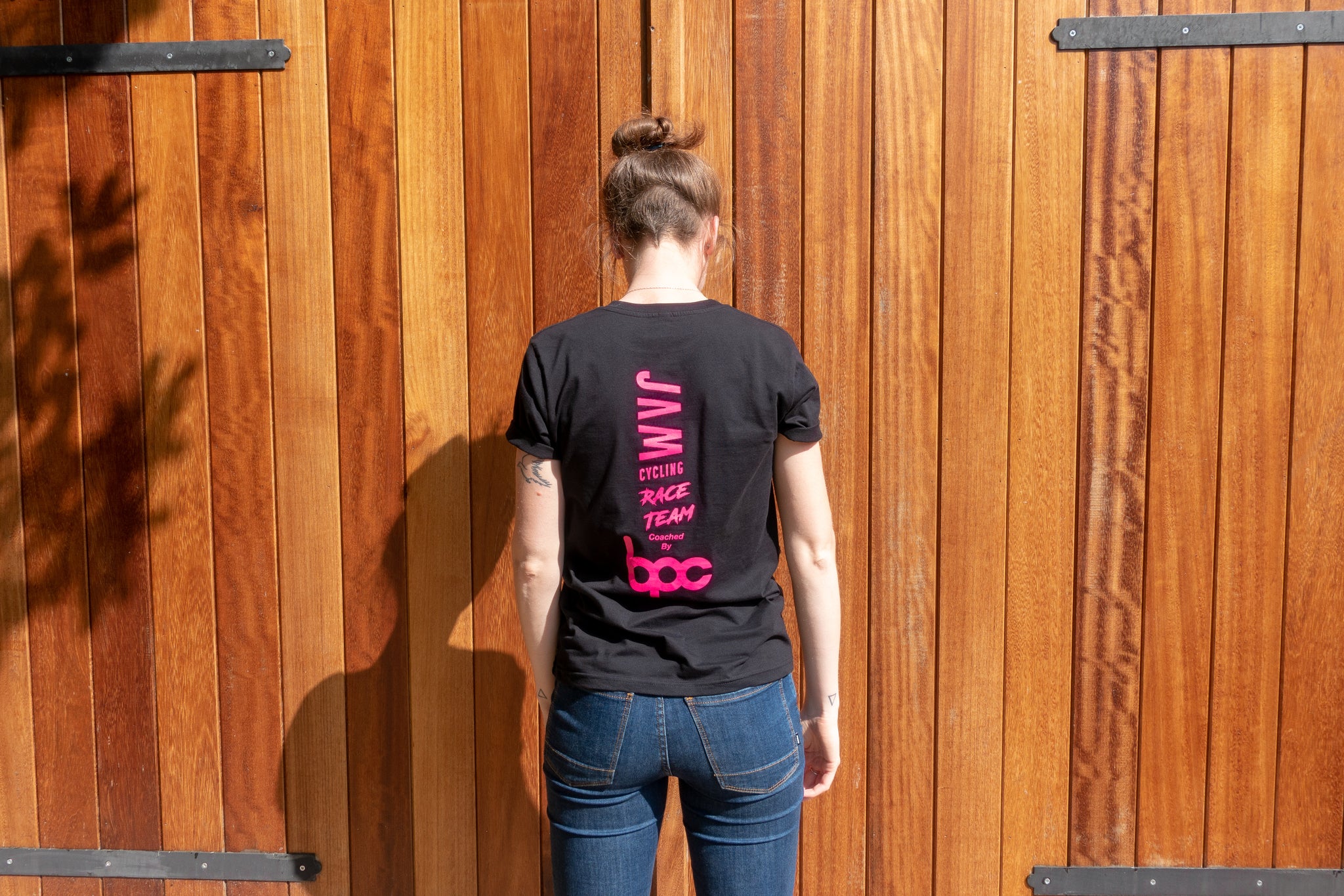 Black JAM Race team t-shirt featuring HOT logos worn by female Jam employee with blue jeans a barn door