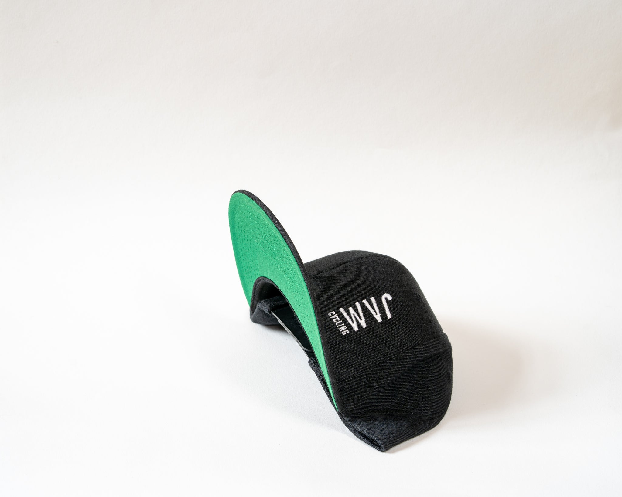 Jam Snapback cap showcasing green base stitched Jam logo symbol sitting on a white background cool product photography