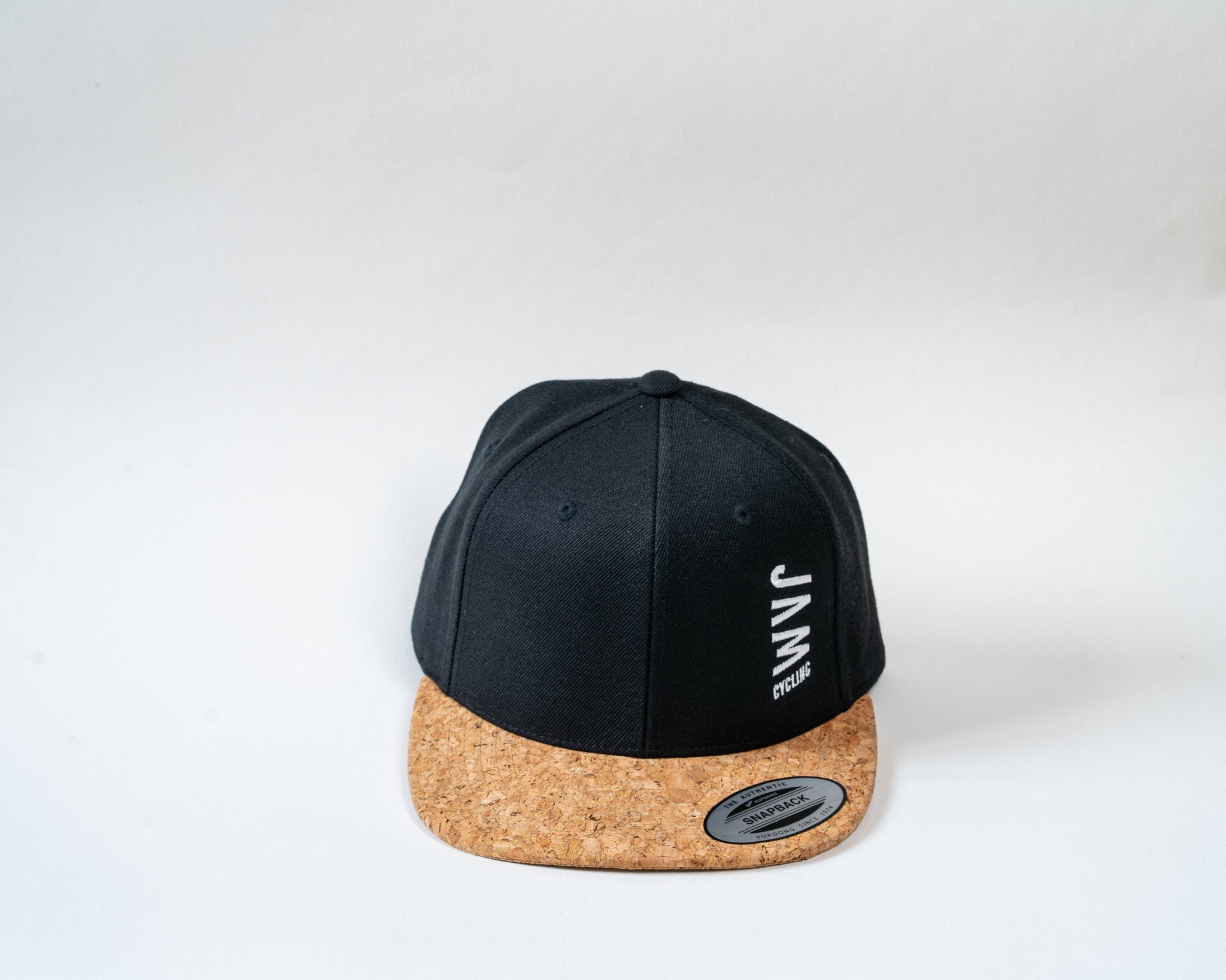 JAM snap back cap featuring cork peak stitched JAM logo floating on a white background